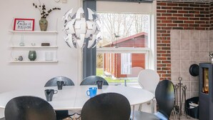 A modern dining area with a white table and black chairs, a decorative spherical light fixture, and a brick fireplace.
