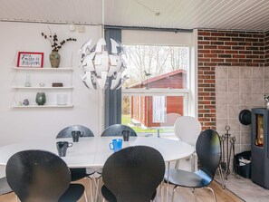 A modern dining area with a white table and black chairs, a decorative spherical light fixture, and a brick fireplace.