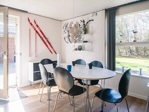 A modern dining room with a round table, black chairs, and a large window with a view of trees. - 6 Person Holiday Home in Hemmet (Hemmet)