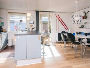 Une cuisine moderne dotée d’un îlot central, d’un coin repas avec une table et des chaises, et d’une horloge murale.
