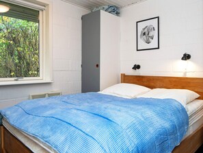 A single bed with a wooden headboard, a blue and white checkered bedspread, and two wall-mounted reading lamps. - 6 Person Holiday Home in Hemmet (Hemmet)