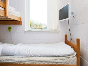 A single bed with a wooden frame and white bedding, a window with a view of trees, and a wall-mounted television. - 6 Person Holiday Home in Hemmet (Hemmet)