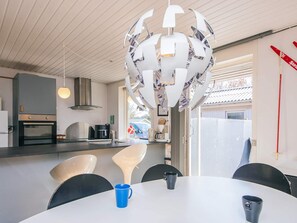 A modern kitchen with a central island, a dining table with chairs, and a unique ceiling light fixture. - 6 Person Holiday Home in Hemmet (Hemmet)