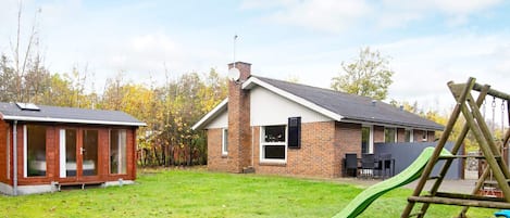 Il s’agit d’une propriété résidentielle comprenant une maison en briques, une structure de jeu en bois et un petit abri de jardin.