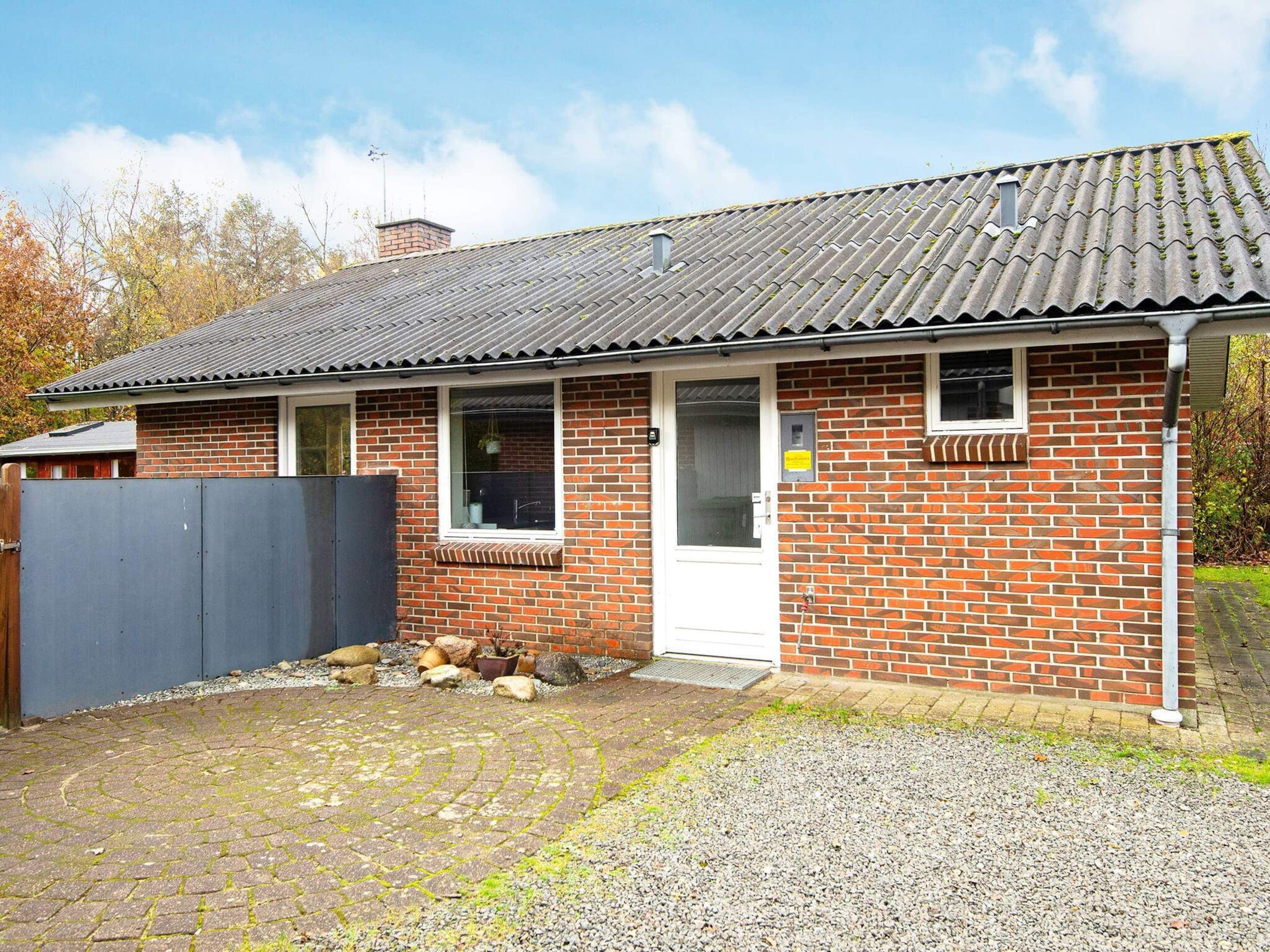 A brick building with a tiled roof, a white door, and a small window.