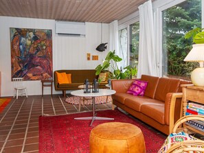 A living room with a brown sofa, a round coffee table, a red patterned rug, and a large abstract painting on the wall. - 4 Person Holiday Home in Ebeltoft (Ebeltoft)