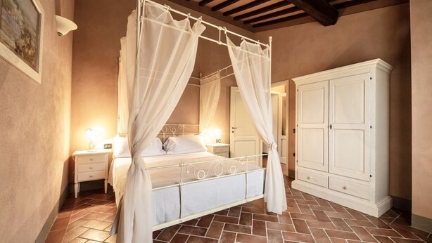 A bedroom with a four-poster bed, a nightstand, a cabinet, and a tiled floor. - Two-room apartment, approximately 38 square meters, sleeps 4. Finely furnished and comprising a kitchenette equipped with dishes, an oven, a refrigerator with freezer, satellite TV, a living room with a double sofa bed, a double bedroom, and a private ba (Monteverdi Marittimo)