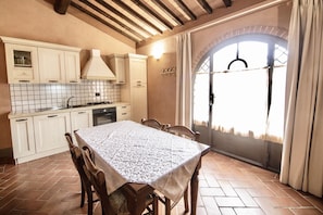 A kitchen with a tiled backsplash, wooden cabinets, a stove, and a dining table with chairs.