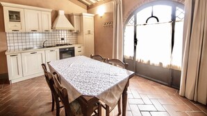A kitchen with a tiled backsplash, wooden cabinets, a stove, and a dining table with chairs. - Two-room apartment, approximately 38 square meters, sleeps 4. Finely furnished and comprising a kitchenette equipped with dishes, an oven, a refrigerator with freezer, satellite TV, a living room with a double sofa bed, a double bedroom, and a private ba (Monteverdi Marittimo)