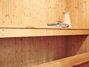 A wooden sauna bench with a towel and a white container on top. - 10 Person Holiday Home in Hojby (Hojby)