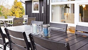 Un espace extérieur aménagé avec des tables et des chaises, une grande fenêtre et une vue sur les arbres.