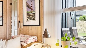 Une pièce chaleureuse avec un mur en bois, un canapé blanc, une table avec une lampe et une affiche encadrée du pont du Golden Gate.