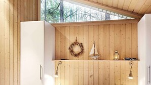 Une chambre avec un plafond en bois, un lit, une étagère ornée d’une guirlande, un modèle de voilier et une lanterne.