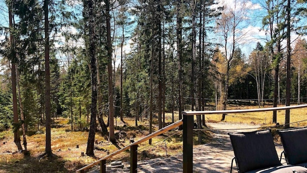 A wooden deck with two chairs and a metal railing overlooking a forested area. - 4 Person Holiday Home in Garphyttan (Garphyttan)