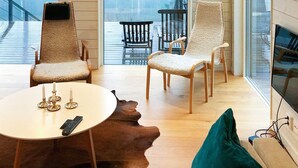 A modern living room with a glass door leading to a deck, two chairs with textured upholstery, a round coffee table, and a leather rug. - 4 Person Holiday Home in Garphyttan (Garphyttan)