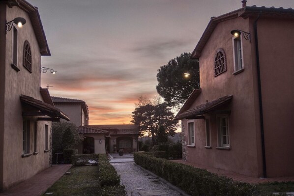 A courtyard with buildings, a pathway, and a sunset.
