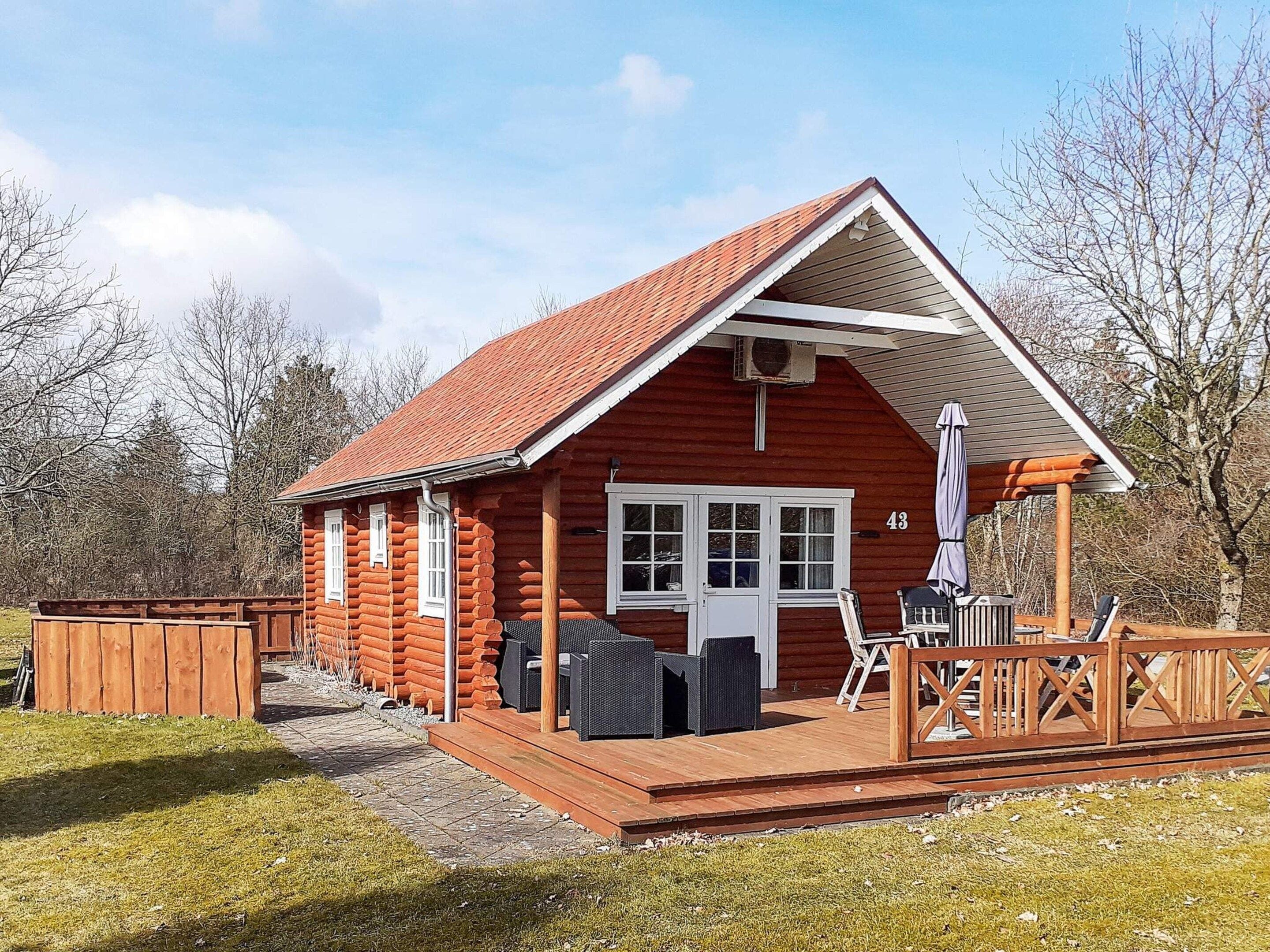 A log cabin with a deck, a covered outdoor seating area, and a number 43 sign.