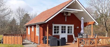 A log cabin with a deck, a covered outdoor seating area, and a number 43 sign.