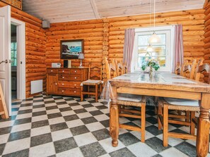 A log cabin interior with a checkered floor, wooden furniture, a dining table, and a painting on the wall. - 6 Person Holiday Home in Hovborg (Hovborg)