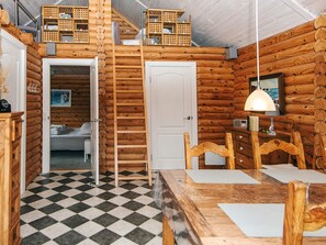 A cozy cabin with a checkered floor, wooden walls, a loft area with storage, and a dining table with chairs. - 6 Person Holiday Home in Hovborg (Hovborg)