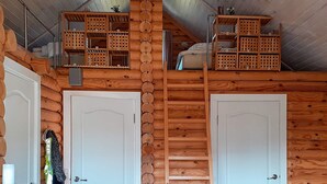 L’intérieur d’une cabane avec deux portes blanches, des étagères en bois et une échelle.