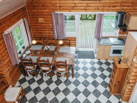 Una cabaña de madera con comedor, cocina y un ventanal grande.