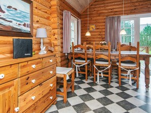 A log cabin interior with a checkered floor, wooden furniture, a dining table set, and a painting on the wall. - 6 Person Holiday Home in Hovborg (Hovborg)