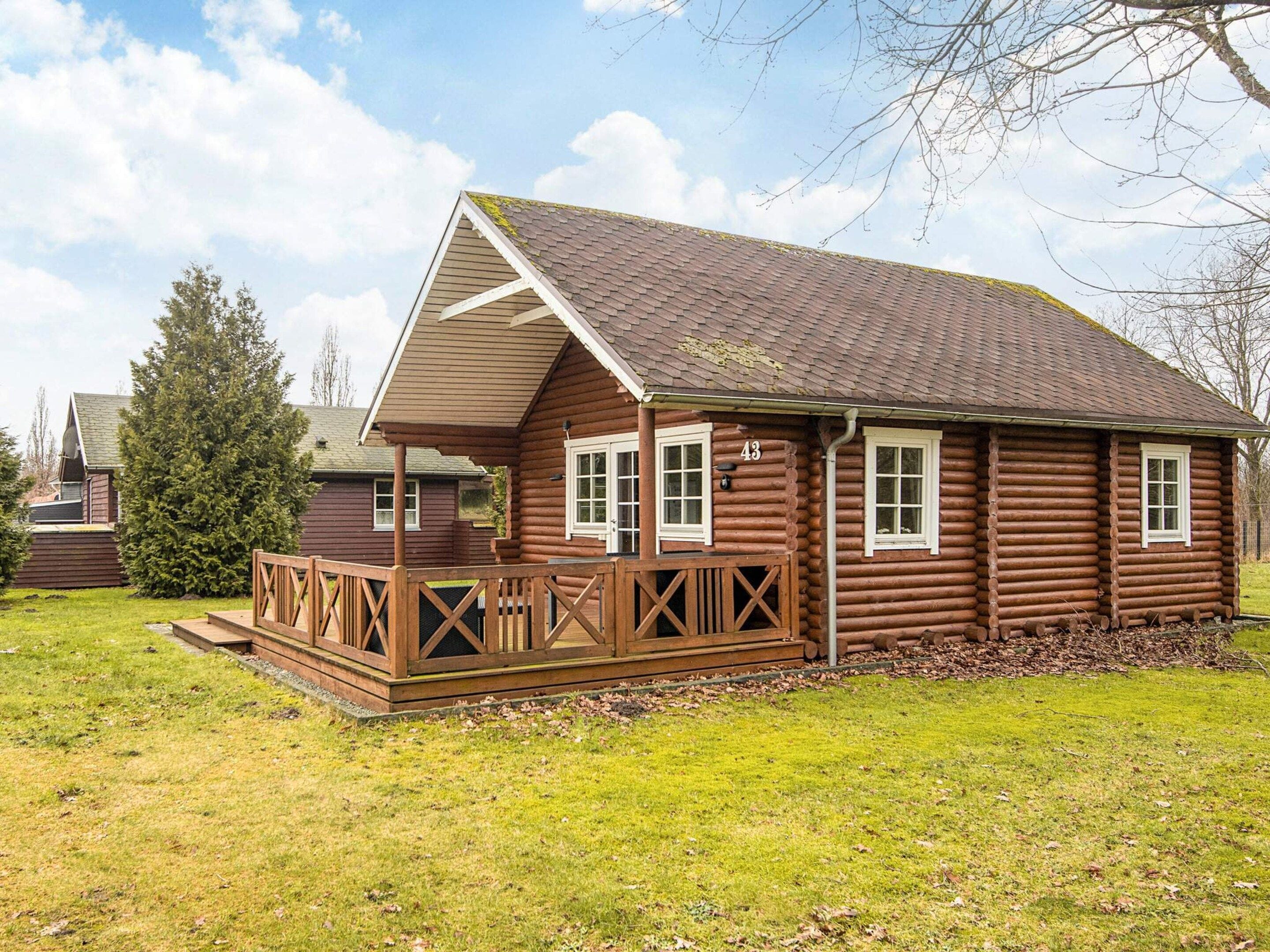 A log cabin with a wooden deck, a pitched roof, and a number '43' on the side.