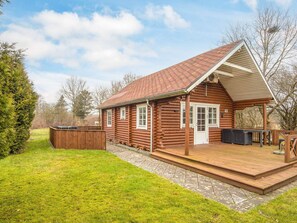 A log cabin with a deck, a covered porch, and a fenced yard. - 6 Person Holiday Home in Hovborg (Hovborg)