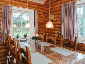 A wooden cabin interior with a dining table, chairs, and a hanging pendant light. - 6 Person Holiday Home in Hovborg (Hovborg)