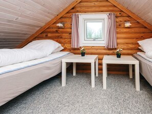 A cozy attic bedroom with two beds, a small window with curtains, and a table with a plant. - 6 Person Holiday Home in Hovborg (Hovborg)
