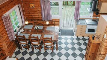 A wooden cabin with a dining area, kitchen, and a large window.