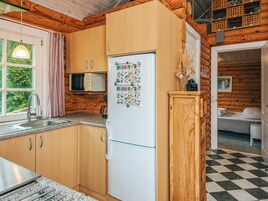 A compact kitchen with wooden cabinets, a white refrigerator, a microwave, and a sink.