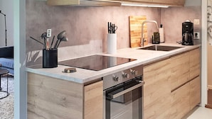 Een moderne keuken met houten kastjes, een inbouwoven, een spoelbak en een aanrecht met een koffiezetapparaat.