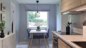 Een moderne keuken met een eethoek, houten kastjes en een raam met uitzicht op groen.