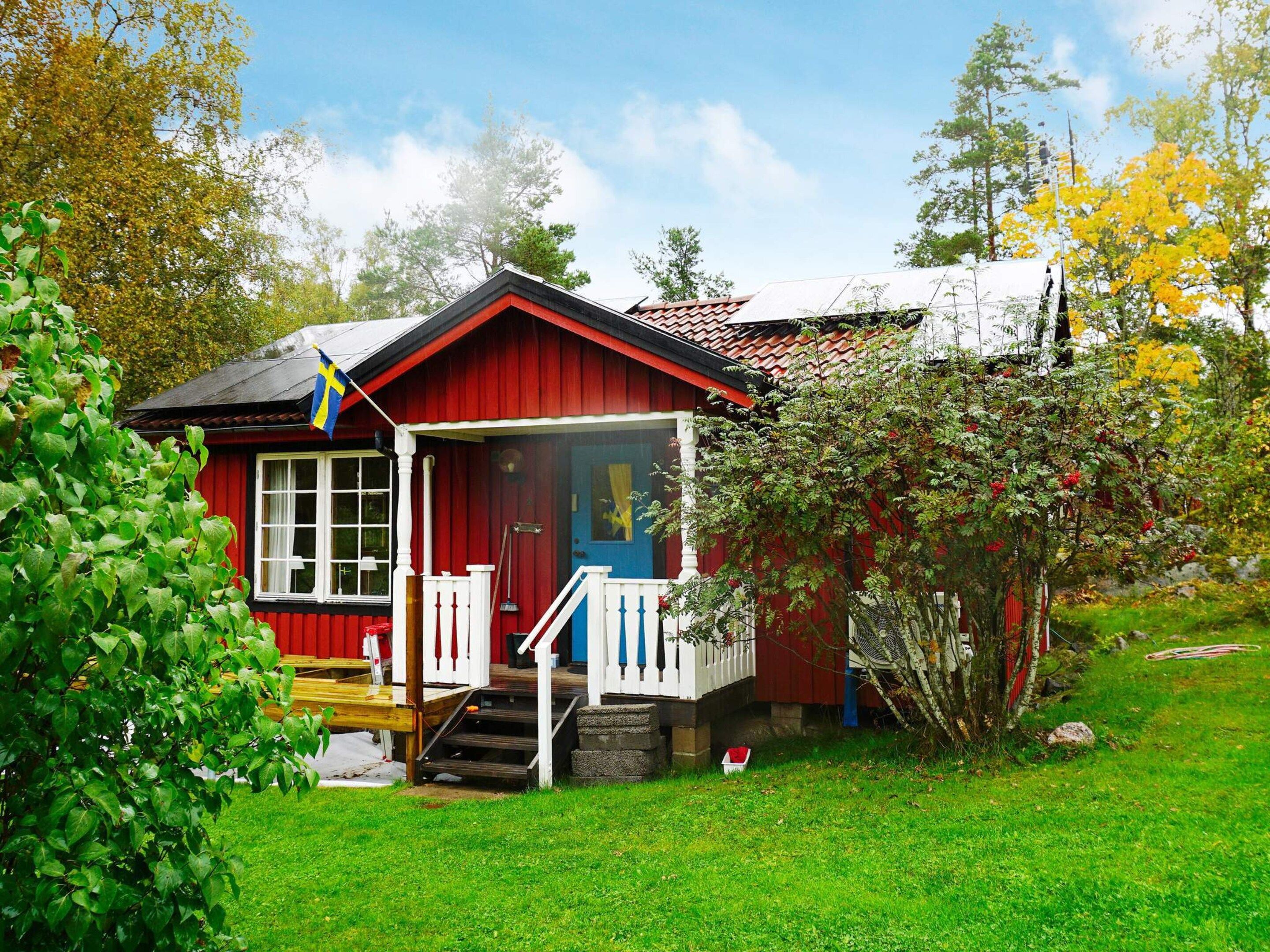A red wooden house with a porch, steps, and a flag.