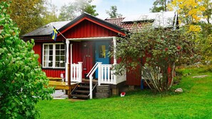 Une maison en bois rouge avec un porche, des marches et un drapeau.