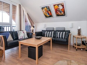 A modern living room with a sofa, a coffee table, and a small side table. There are two abstract paintings on the wall and a lamp on the side table.