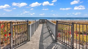 A wooden boardwalk leading to a beach with a clear sky and distant ocean view. - NEW! 10th Floor! Tip-Sea Turtle, Beach View! (Myrtle Beach)