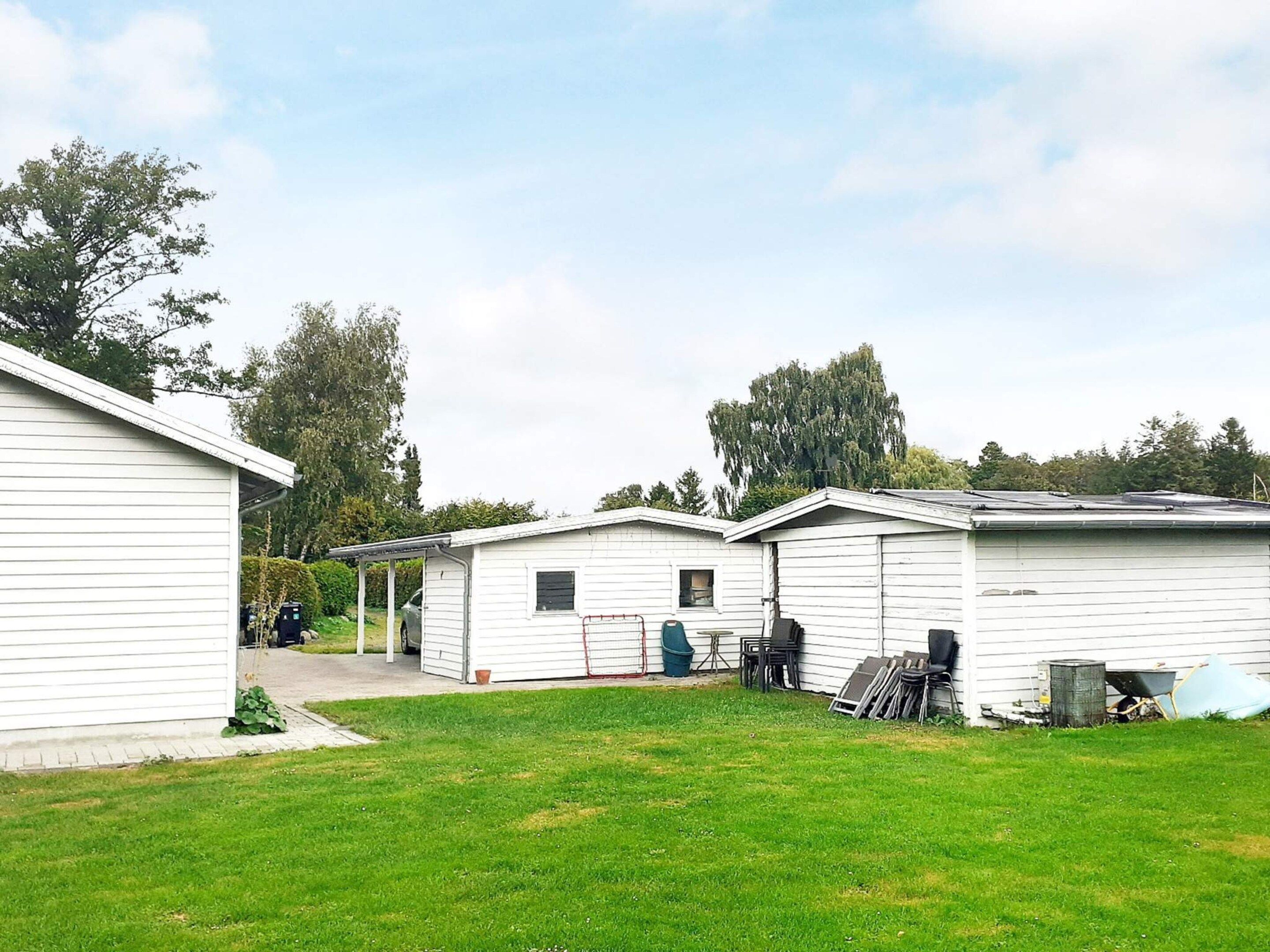 A row of white mobile homes with a grassy yard in front.