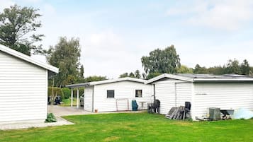 A row of white mobile homes with a grassy yard in front.