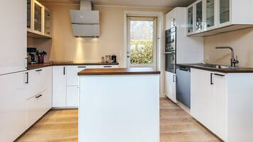 A modern kitchen with white cabinetry, a central island, and built-in appliances.