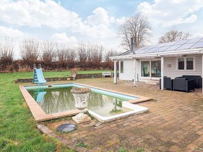 A swimming pool with a slide, a patio with outdoor furniture, and a house with solar panels. - 4 Star Holiday Home in Rodvig Stevns (Rodvig Stevns)