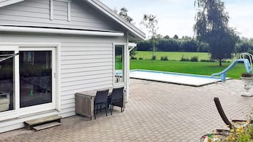 Una casa con patio, piscina y jardín cubierto de césped.
