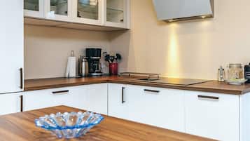 A modern kitchen with white cabinets, a wooden countertop, and a glass bowl on the table.
