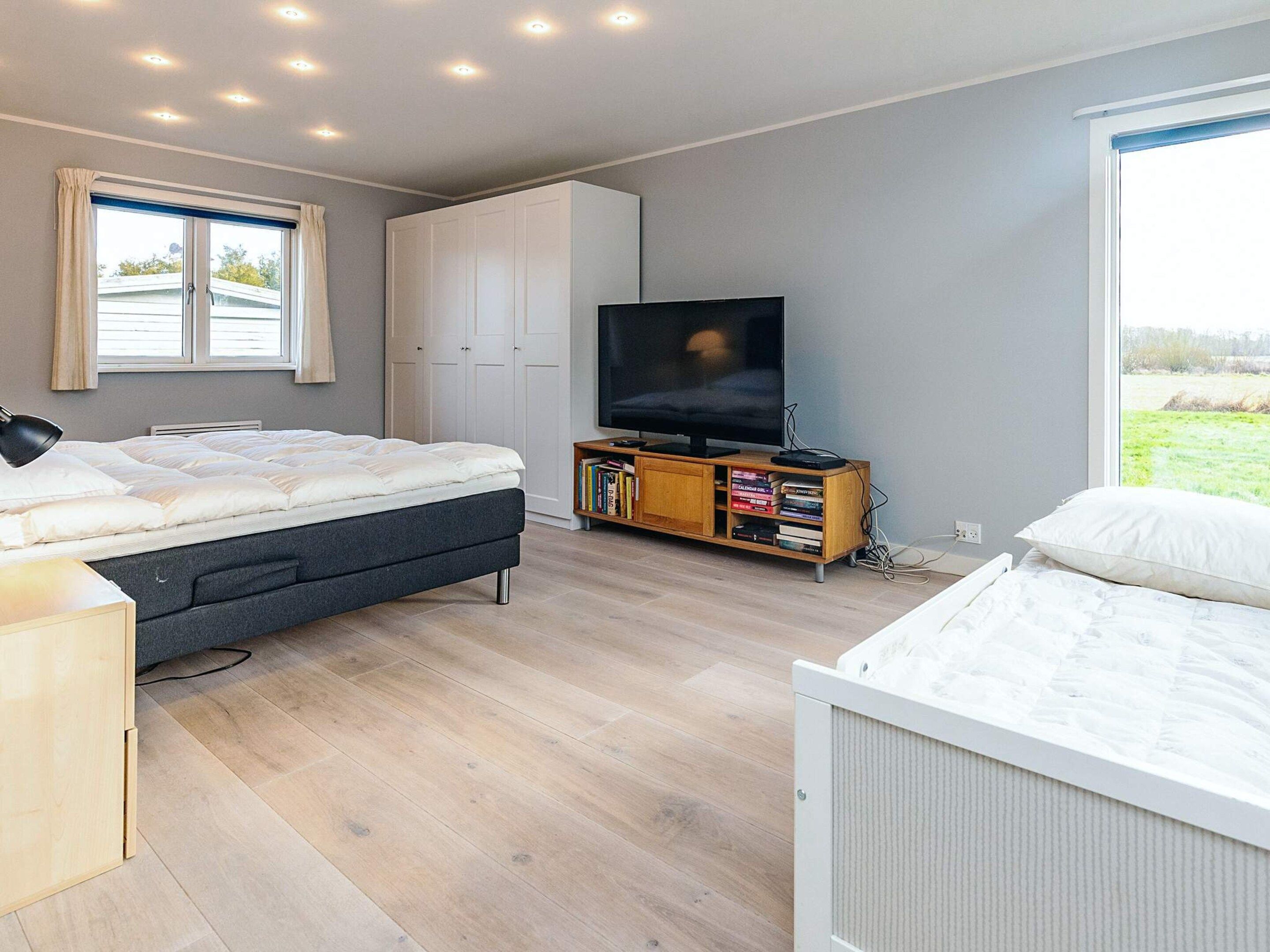 A bedroom with a bed, a TV, a bookshelf, and a wardrobe.