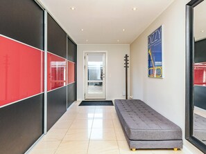 A hallway with a grey sofa, a door, and a poster on the wall. - 4 Star Holiday Home in Rodvig Stevns (Rodvig Stevns)