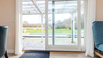 A room with a sliding glass door leading to an outdoor area with a paved walkway and greenery.
