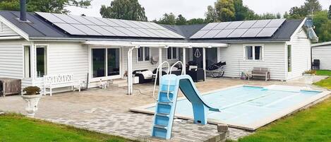Ein Haus mit Swimmingpool, Rutsche und Solaranlage auf dem Dach.