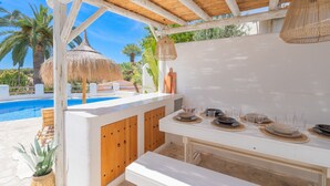 A poolside bar area with a wooden pergola, thatched umbrellas, and a white table set with plates and glasses. - CostaBlancaDreams - Casa Juleo in Benissa (Benissa)